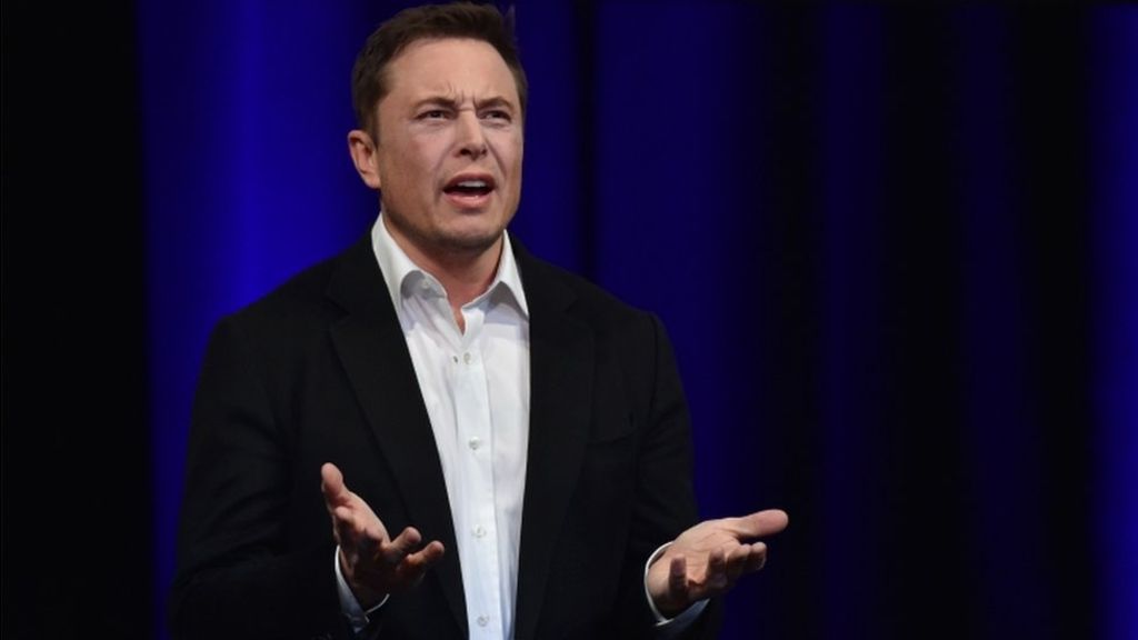 Elon Musk dengan setelah jas tampak sedang berbicara di sebuah acara resmi